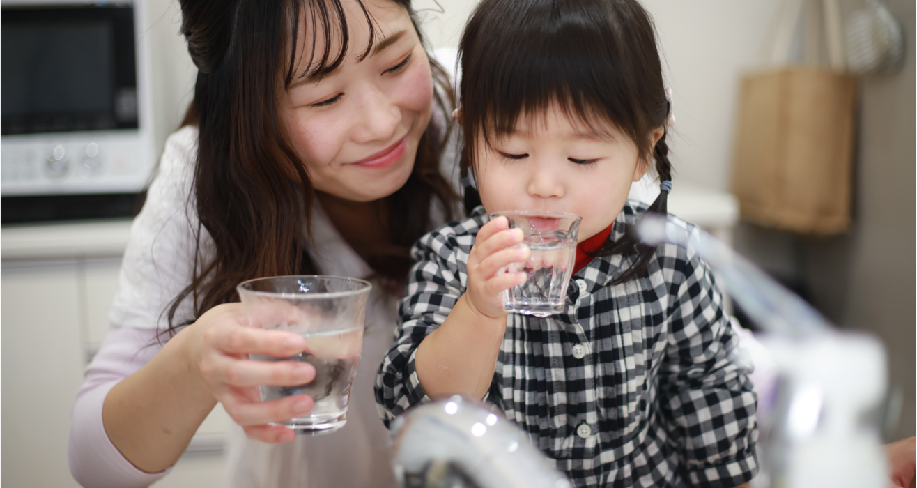 a mother and daughter drinking water at home
